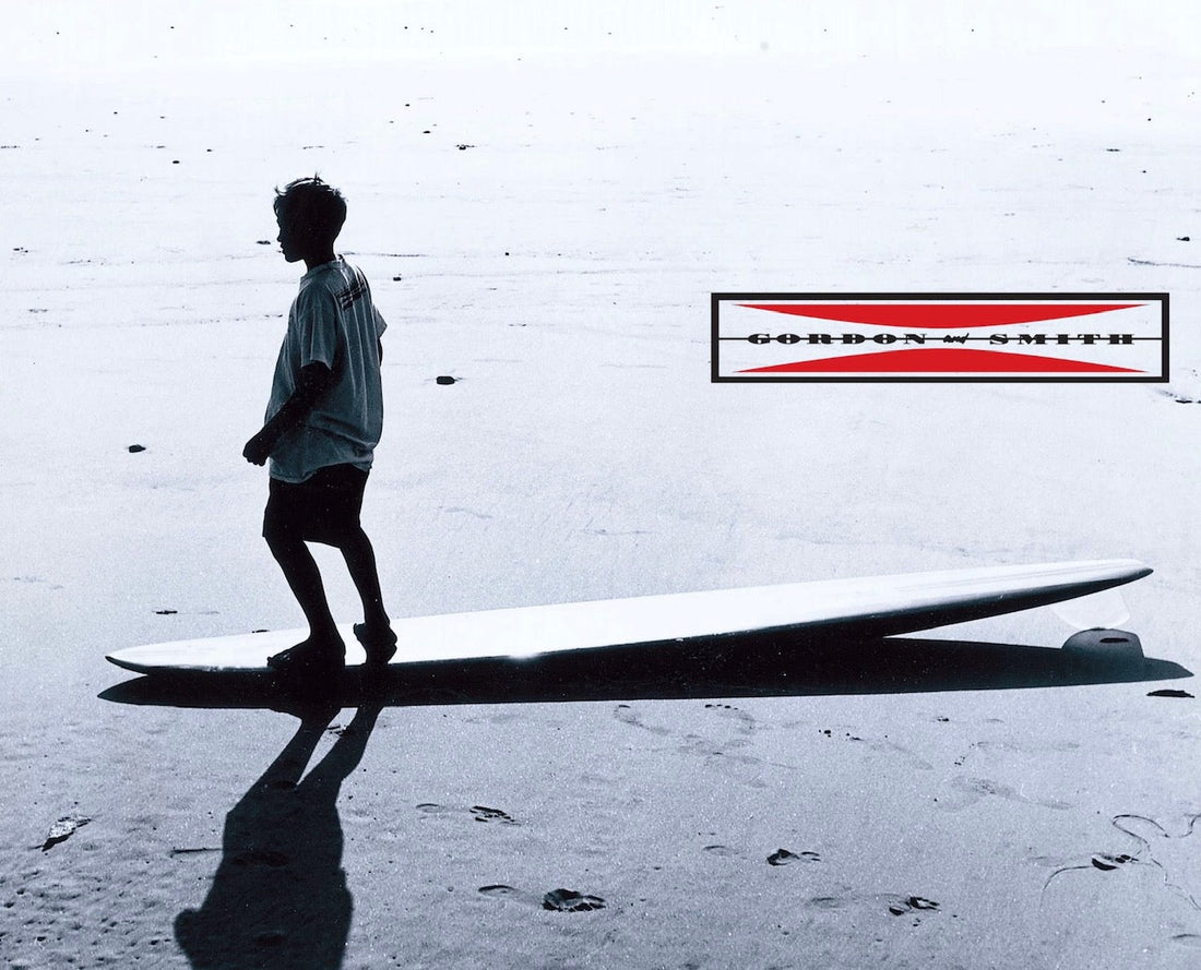 Young Hank Warner hanging 5 on a beached surfboard